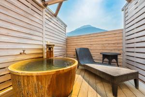 a hot tub with a bench and a table on a deck at Beppu Fuga in Beppu