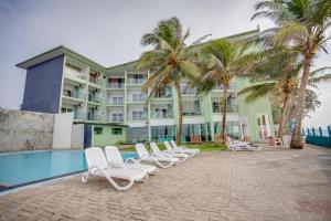 a row of white lounge chairs next to a hotel at Hikkaduwa Beach Hotel in Hikkaduwa