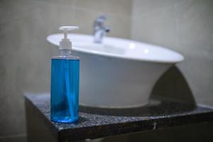 una bottiglia di sapone blu seduta su un bancone accanto a un lavandino di Millennium Continental a Cochin