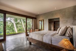 a bedroom with a large bed and a large window at Hidden Gem Suites Ubud in Ubud