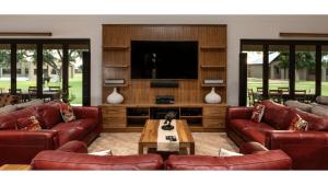 a living room with red leather couches and a tv at Sandune Game Lodge in Gobabis