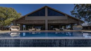 a house with a swimming pool in front of a building at Sandune Game Lodge in Gobabis