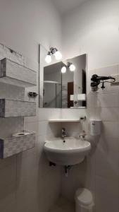 a white bathroom with a sink and a mirror at Apartments Kapus Center in Bled