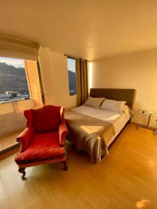 1 dormitorio con 1 cama y 1 silla roja en Providencia Plaza en Santiago