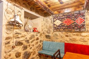Mestia Hotel Amirani في ميستيا: غرفة بها كرسي أزرق وجدار حجري