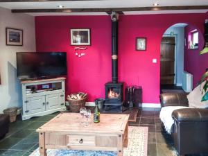 a living room with a red wall with a wood stove at Panteg Cottage in Cross Inn