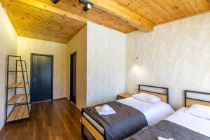 Mestia Hotel Amirani في ميستيا: غرفة نوم بسريرين وسقف خشبي