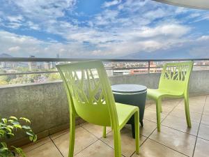 2 sillas verdes en un balcón con vistas en Providencia Plaza, en Santiago