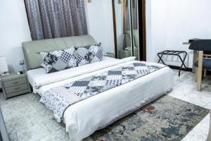 1 dormitorio con cama con edredón y almohadas en Hill View Hotel West Airport en Accra