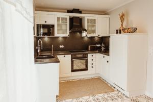 una cocina con armarios blancos y fregadero en Waldchalet Am Steinberg, en Wernigerode