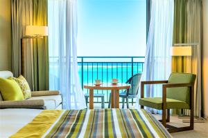 ein Hotelzimmer mit einem Bett, einem Tisch und Stühlen in der Unterkunft Southern Beach Hotel & Resort in Itoman