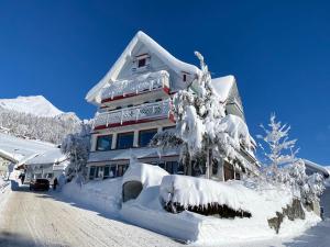 un edificio ricoperto di neve con un albero ricoperto di neve di Gasthaus Friedegg a Wildhaus
