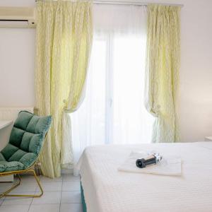 a bedroom with a bed and a green chair and window at Hotel Papanikolaou in Ierissos