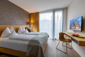 a hotel room with a large bed and a desk at Hotel Katharinenhof COMFORT in Dornbirn