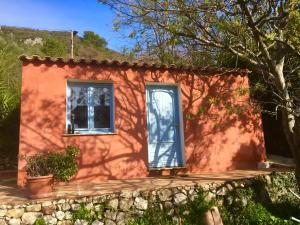 una pequeña casa roja con una puerta azul y ventanas en Magnifique studio dans maisonnette, en Tourrettes-sur-Loup