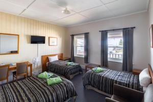 una camera d'albergo con due letti e un tavolo di The Victoria Hotel a Port MacDonnell