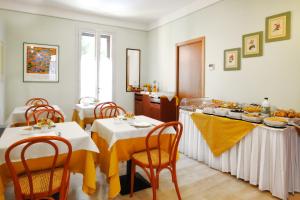 a dining room with two tables with yellow table cloth at Hotel Ziò Imola in Imola