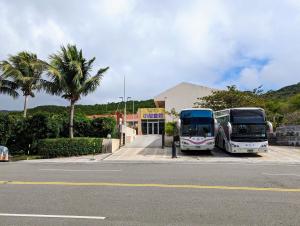 two buses parked in a parking lot next to a building at Howard Kenting Wonder House in Kenting