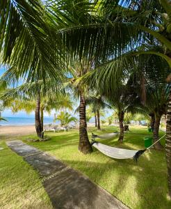 a hammock in the shade of palm trees on a beach at Gold Coast Phu Quoc Beach Resort in Phú Quốc