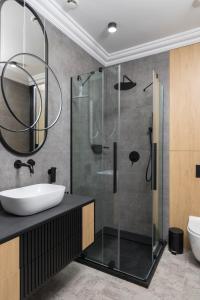 La salle de bains est pourvue d'une douche en verre et d'un lavabo. dans l'établissement Apartamenty Par La Mer, à Niechorze