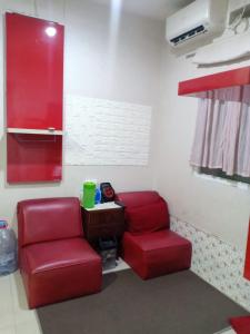 duas cadeiras vermelhas e uma mesa num quarto em Comfort 2BR green pramuka bougenvile em Jakarta