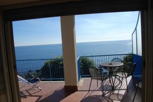 balcón con mesa, sillas y vistas al océano en Casa Il Delfino, en Aci Castello