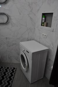 a washing machine in a bathroom with a tile wall at Dwell Apartments in Kremenchuk