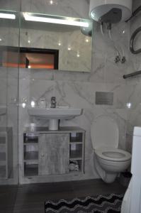 a bathroom with a white toilet and a sink at Dwell Apartments in Kremenchuk
