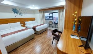 Habitación de hotel con 2 camas y escritorio con TV. en 456 Hotel en Baguio