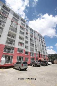 a large apartment building with cars parked in a parking lot at Darah Pines' Homestay in Baguio