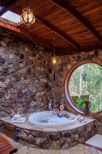 a woman in a bath tub in a stone wall at Pousada Rancho Das Framboesas in Visconde De Maua