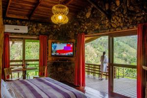 a bedroom with a bed and a tv in a room at Pousada Rancho Das Framboesas in Visconde De Maua
