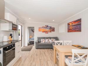 eine Küche und ein Wohnzimmer mit einem Tisch und einem Sofa in der Unterkunft Chill-out Beach Bach - Whangamata Holiday Home in Whangamata