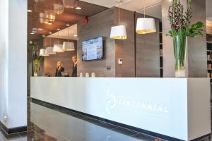 a reception counter in a lobby with a man and a woman at Centennial Nexus Hotel Tallinn in Tallinn