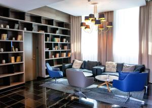 a living room with a couch and chairs and bookshelves at Centennial Nexus Hotel Tallinn in Tallinn