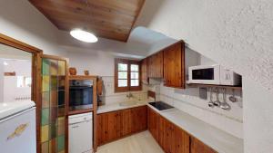 una cucina con armadietti in legno ed elettrodomestici bianchi di Agroturisme Can Burguès a Santa Eulalia de Ronsaná