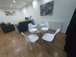 a dining room with a table and white chairs at Luxury 5 - Spacious Contractor's Delight with 4 Bedrooms and Ample Driveway Parking in Luton