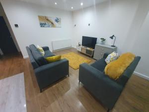 a living room with two couches and a television at Luxury 5 - Spacious Contractor's Delight with 4 Bedrooms and Ample Driveway Parking in Luton +23 photos