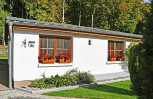 a white building with two windows and red flowers at Ferienwohnung an der Granitz in Ostseebad Sellin +8 photos