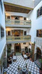 an indoor courtyard with chairs and a balcony at Riad Green House in Fès