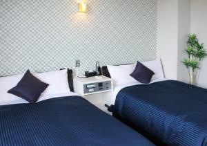 a bedroom with two beds with blue and white pillows at Hotel Livemax BUDGET Kanazawa-Idaimae in Uchinada