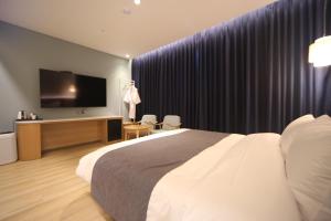 釜山にあるHound Hotel Junggwanのベッド1台、薄型テレビが備わるホテルルームです。