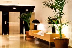 a lobby with two potted plants and a desk at NH Madrid Principe de Vergara in Madrid