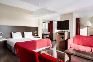 NH Arnhem Rijnhotel في آرنم: غرفة فندق بسرير واريكة حمراء