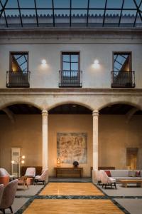 uma grande sala com cadeiras e mesas num edifício em NH Collection Salamanca Palacio de Castellanos em Salamanca