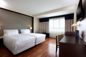 a hotel room with a large white bed and a desk at NH Canciller Ayala Vitoria in Vitoria-Gasteiz