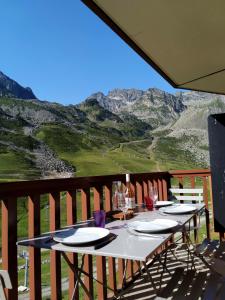 una mesa con platos y copas de vino en el balcón en Superbe appartement vue panoramique pied des pistes, en La Mongie