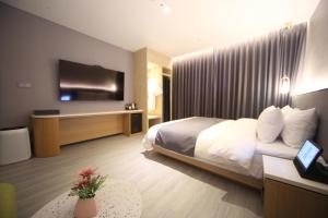 a hotel room with a bed and a flat screen tv at Hound Hotel Junggwan in Busan