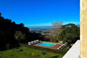 a swimming pool in a garden with chairs and a view at Tivoli Palacio de Seteais - The Leading Hotels of the World in Sintra