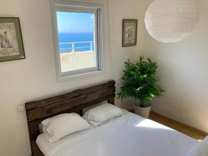 a bedroom with a bed with a window and a plant at Seawave Panthouse in Netanya